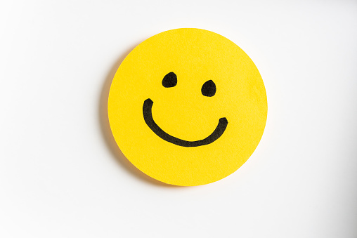 drawing of a happy smiling emoticon on a yellow paper and white background